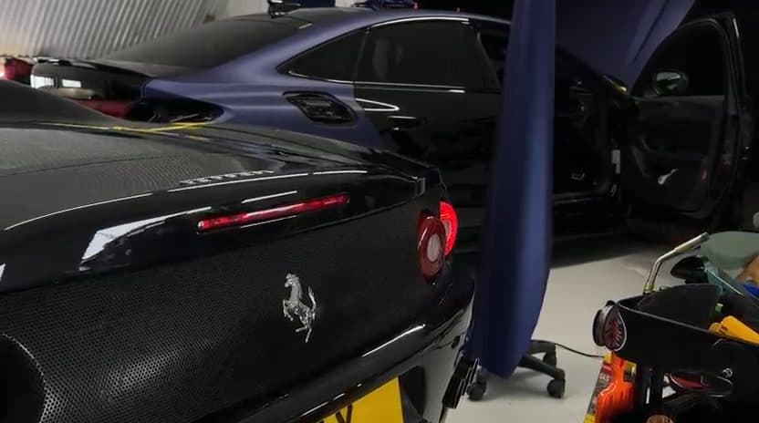 Rear of a black Ferrari, carbon deck and badge, tool trolley alongside